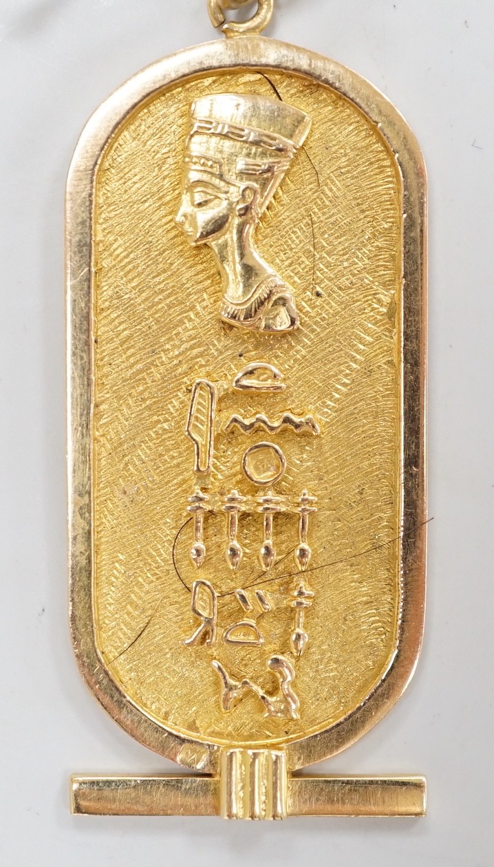 An Egyptian yellow metal pendant, overall 57mm, on a 750 chain, 57cm, gross weight 12.4 grams.